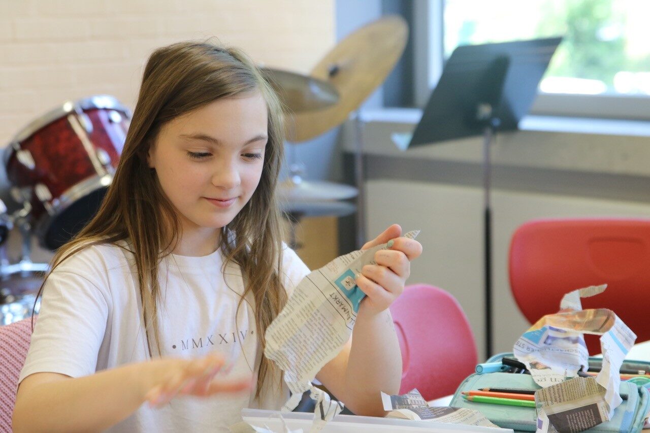 Schüler im Musikunterricht formen Zeitungspapier für ein Projekt der Neuen Musik