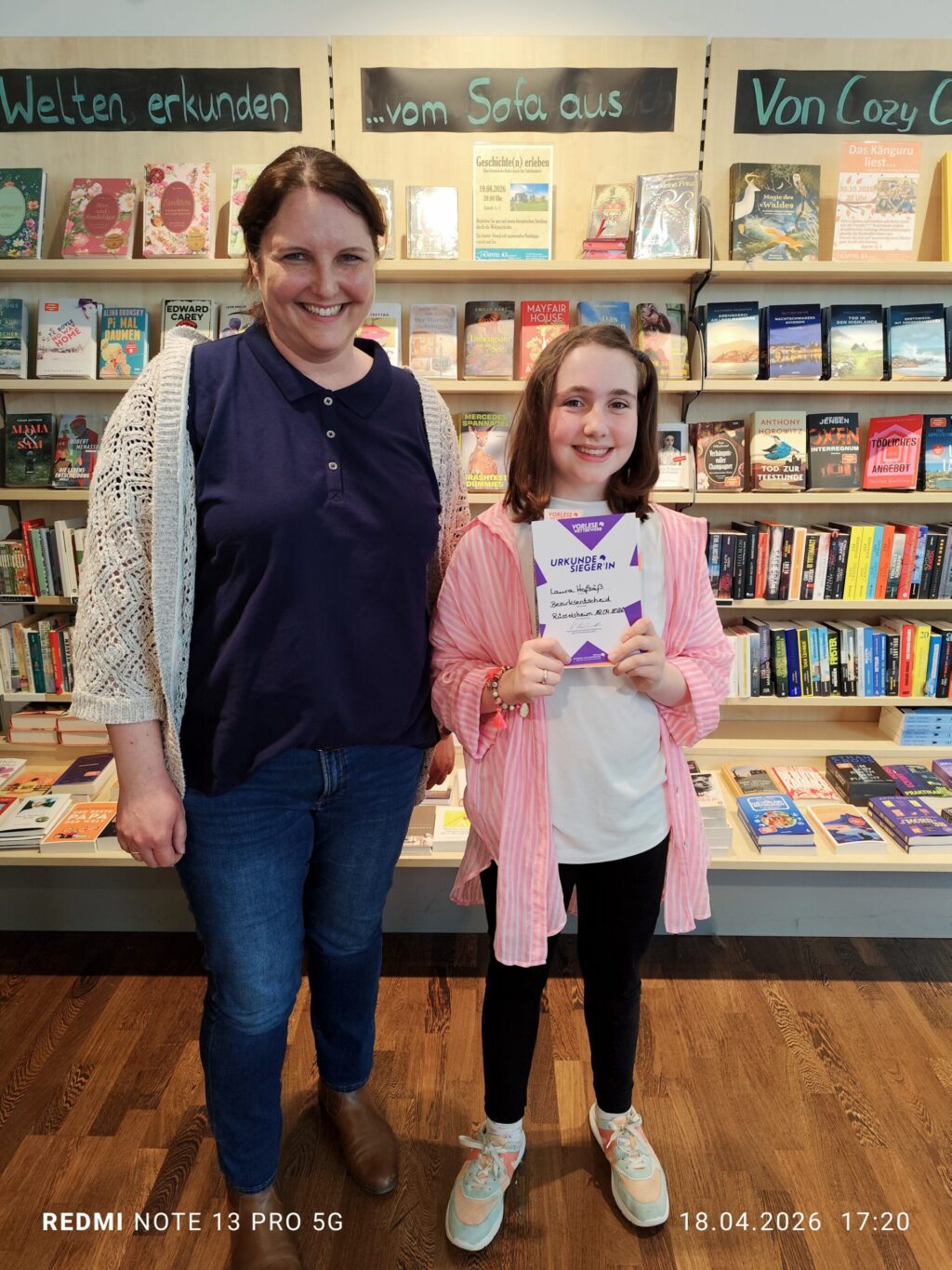 Schülerin und Lehrerin in der Buchhandlung nach dem Sieg von Schülerin beim Vorlesewettbewerb