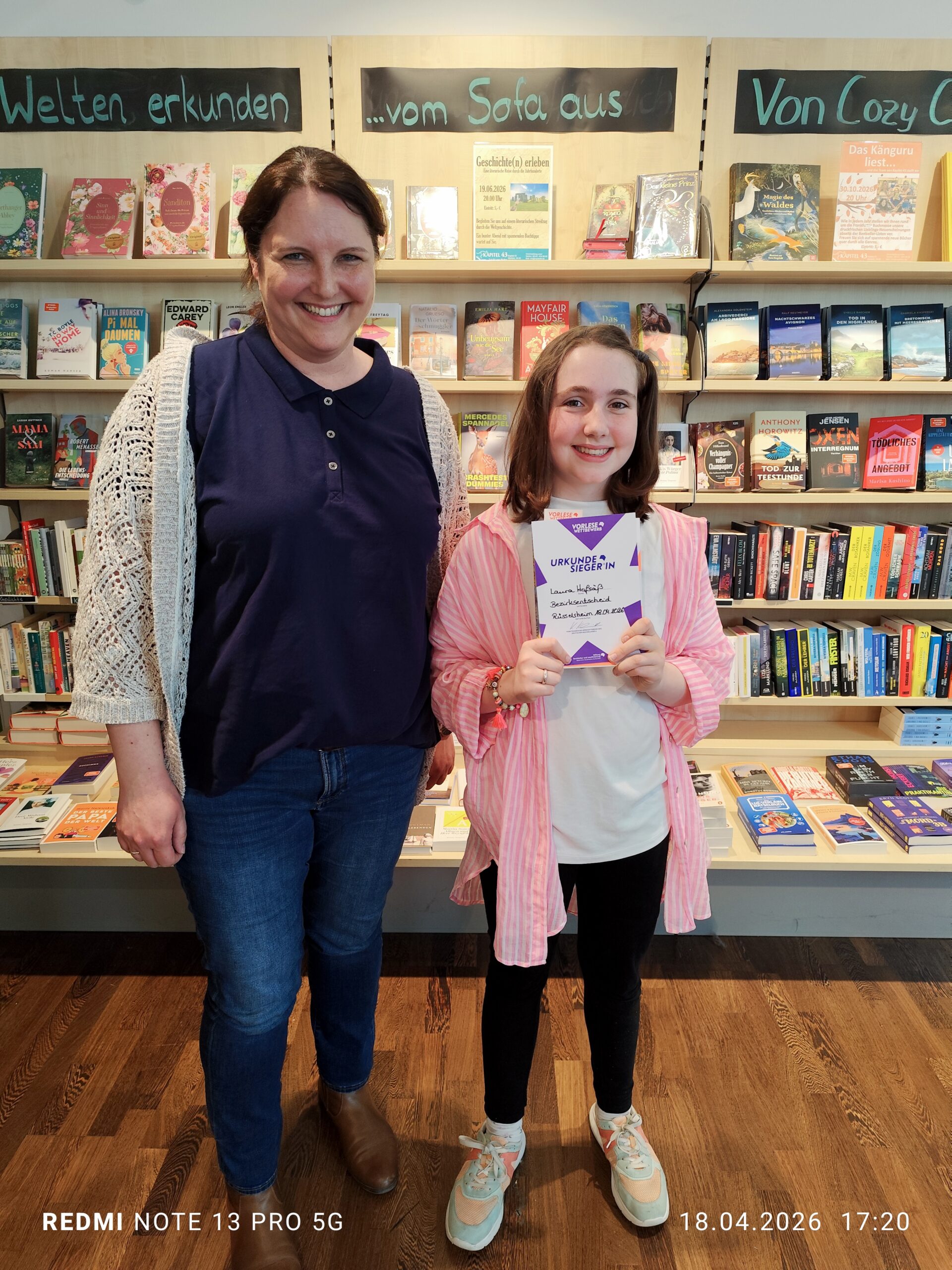 Schülerin und Lehrerin in der Buchhandlung nach dem Sieg von Schülerin beim Vorlesewettbewerb